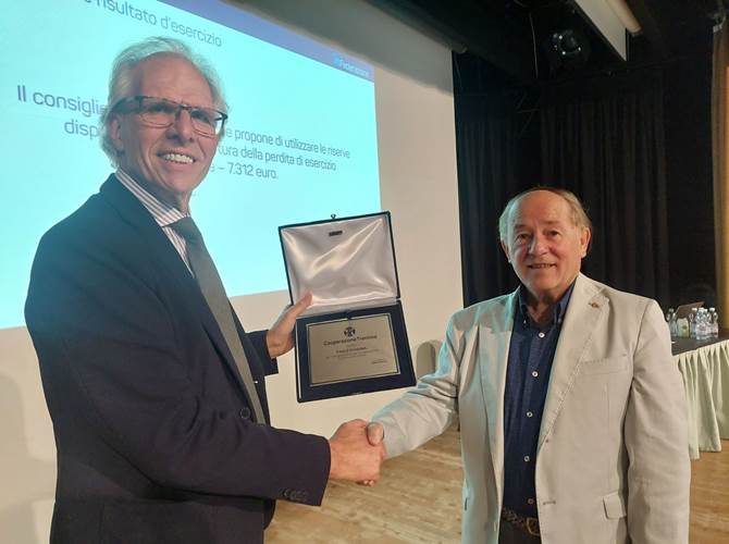 Da sinistra Walter Liber, responsabile area stampa e comunicazione della Cooperazione Trentina, consegna il riconoscimento a Chiogna